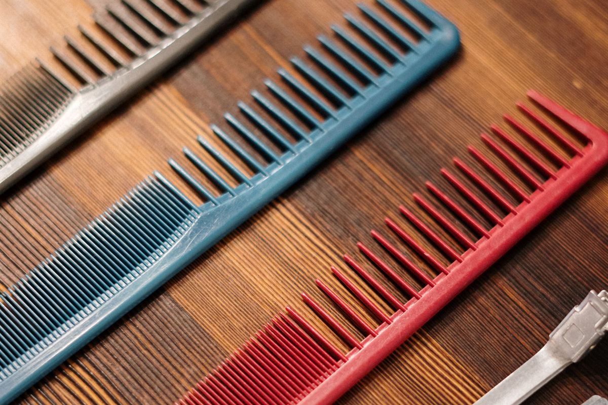 Un peine de acero, uno azul y uno rojo alineados sobre el mesón de madera, con las navajas al lado