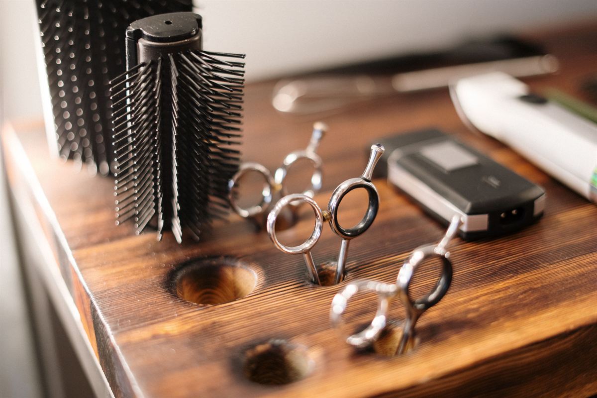 Dos tijeras de barbero apoyadas en el canto del mesón de madera