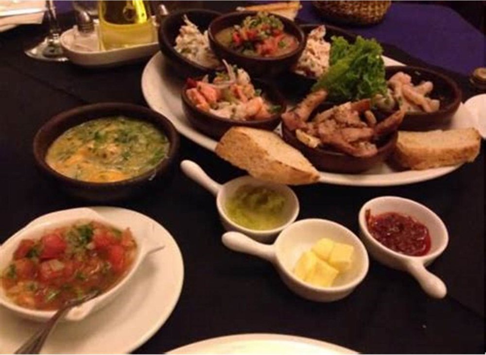 Mariscos, pebre y pan servidos en fuentes de greda para picotear.