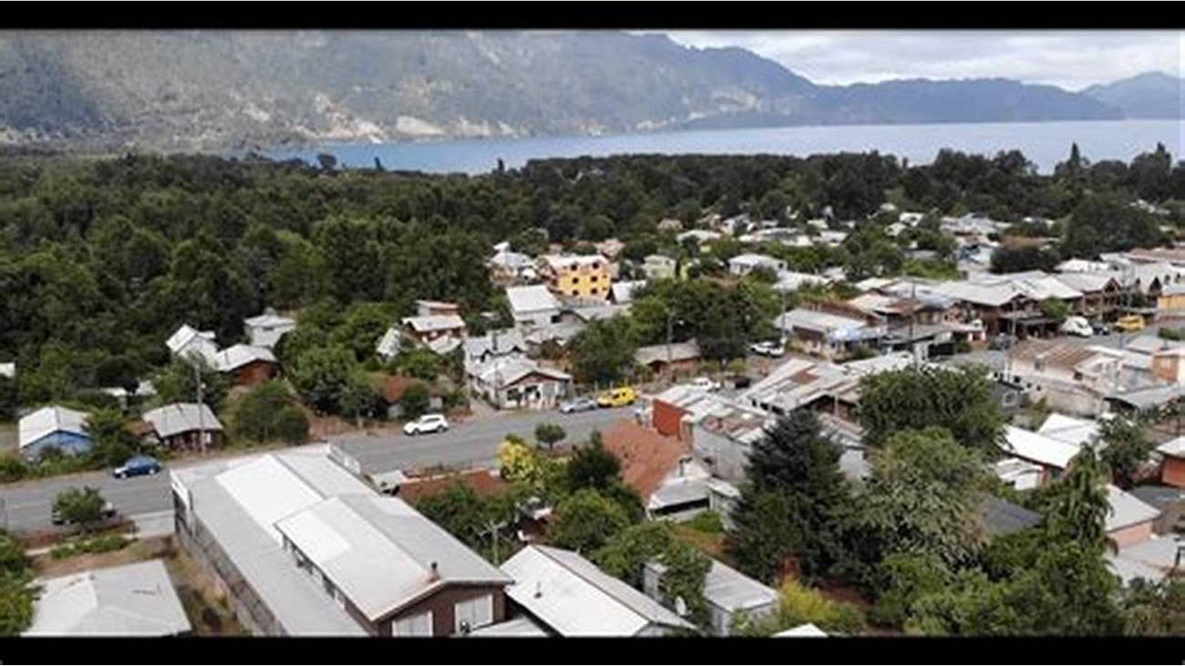 Coñaripe visto desde arriba, con el pueblo entre los árboles y el lago al fondo.