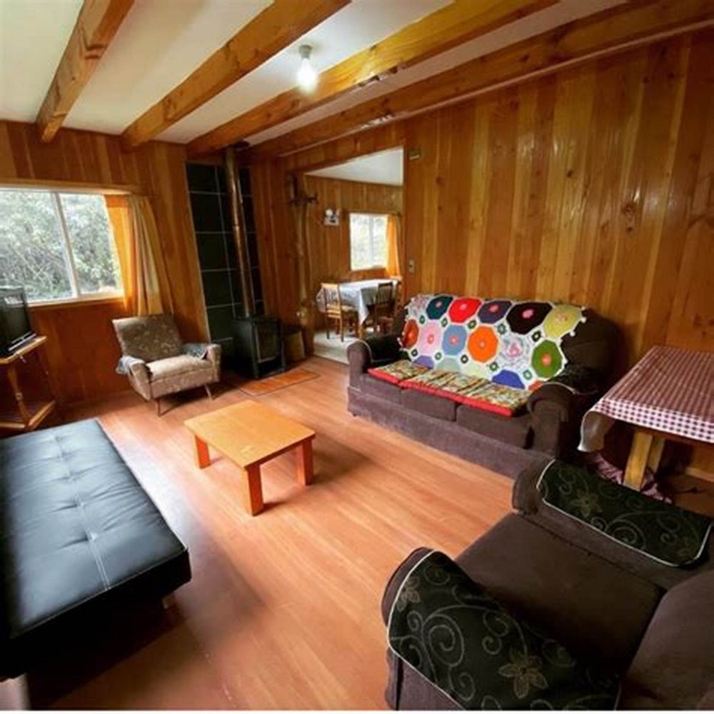 El living con sus sofás, la mesa de centro y la estufa a leña al fondo.