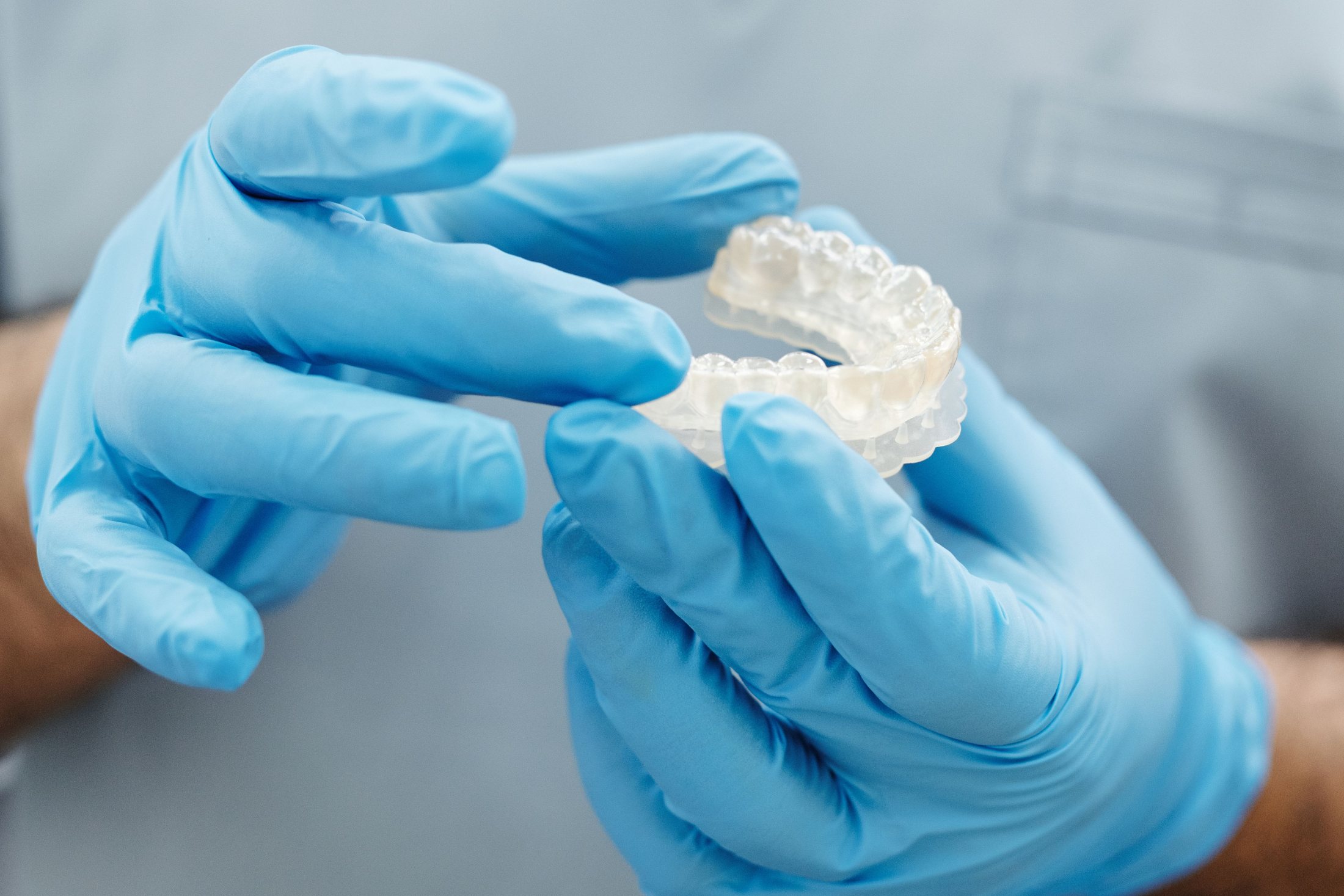 Manos con guantes sosteniendo un alineador transparente