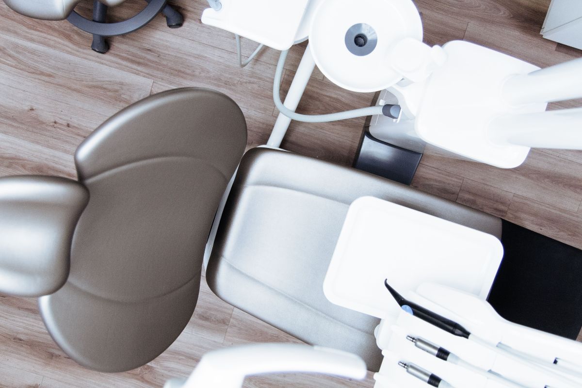 Sillón dental visto desde arriba, con la bandeja de instrumental sobre el piso de madera