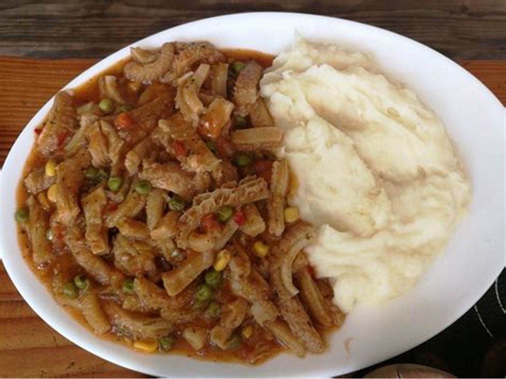 Guiso con puré, servido en plato hondo.