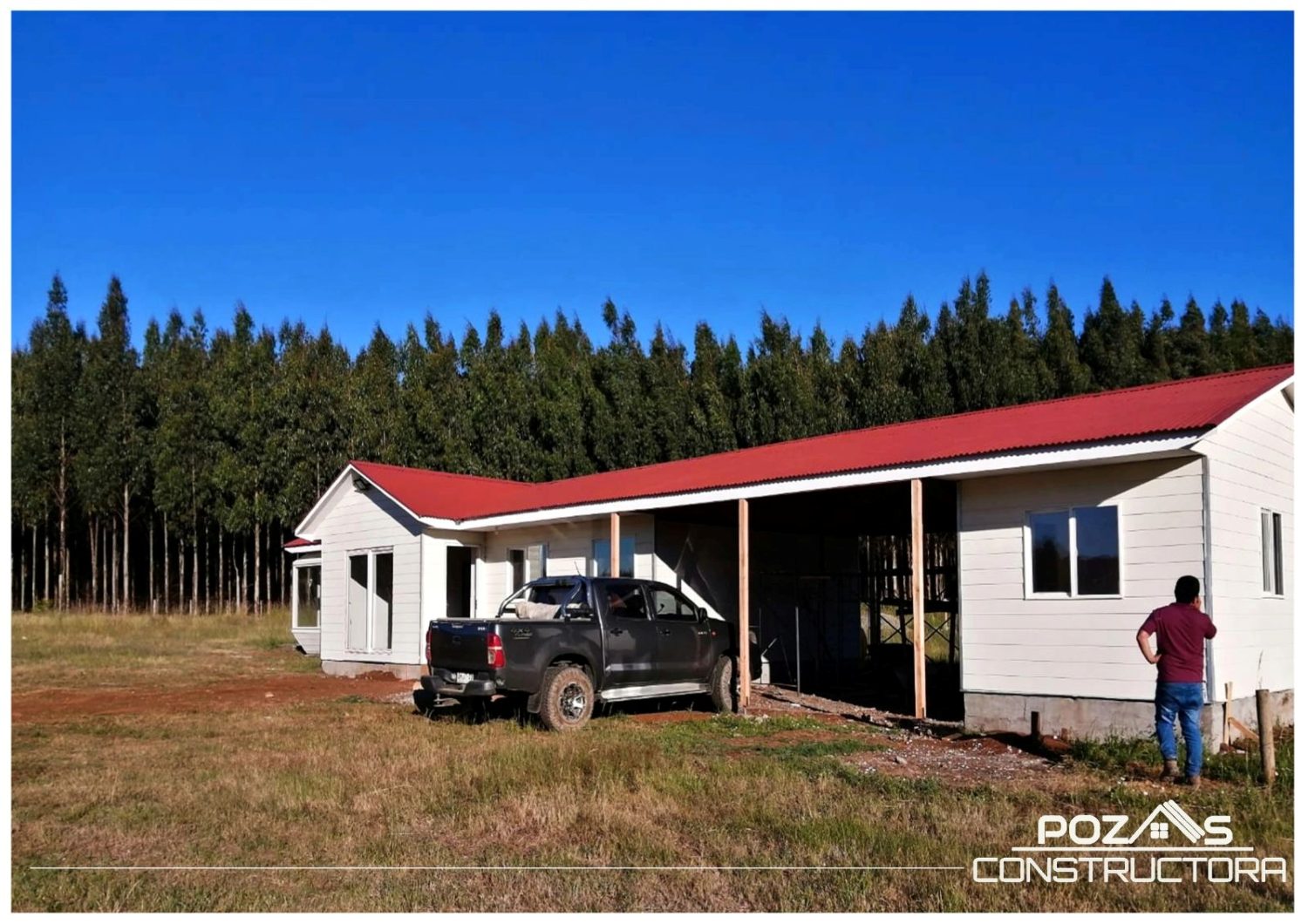 Casa de techo rojo en obra, con el corredor todavía sin cerrar y una camioneta al lado.