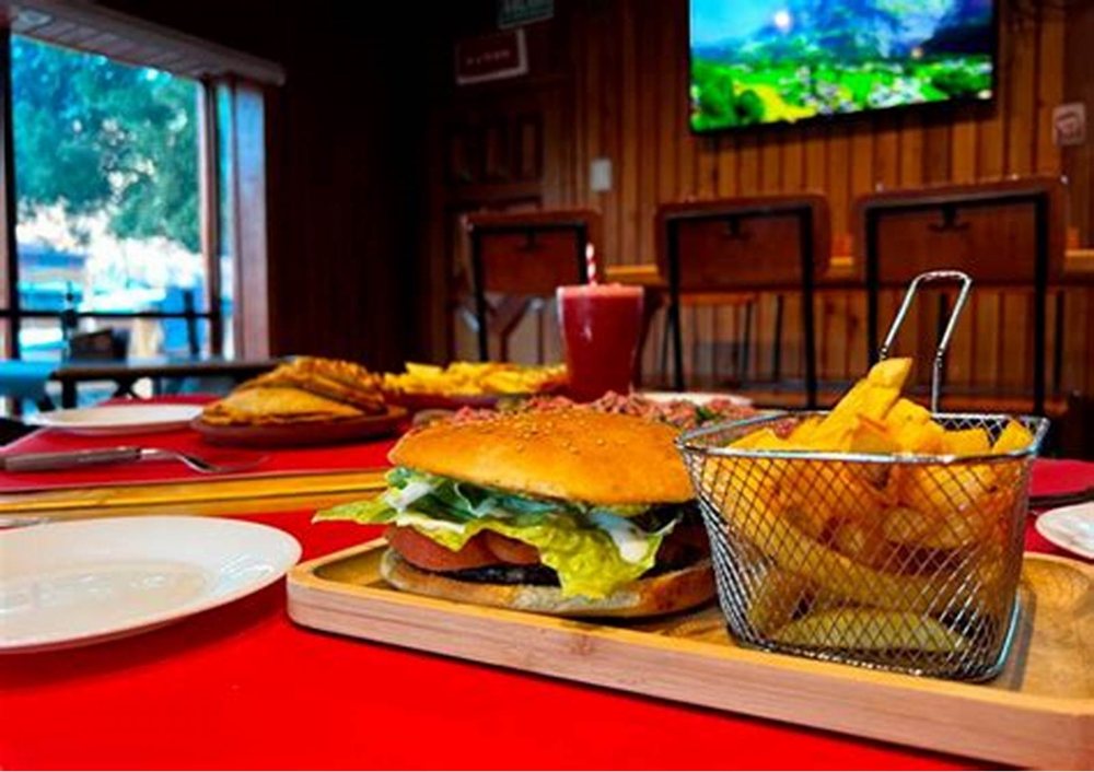 Una hamburguesa con papas fritas en canasta, sobre la tabla.