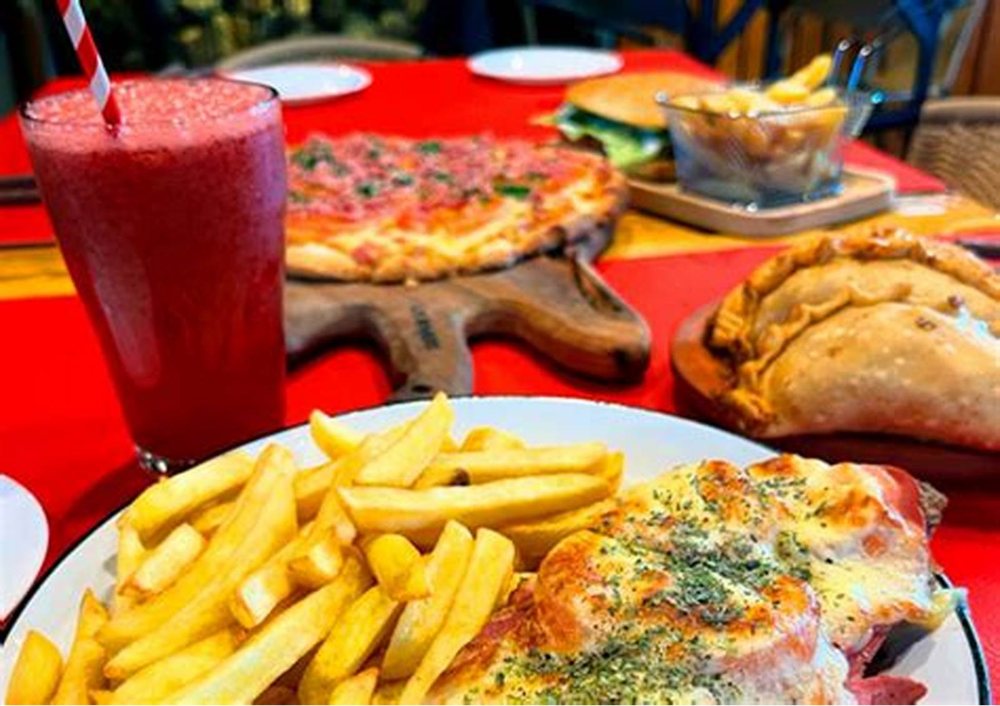 Pizza, empanadas y papas servidas en la mesa.