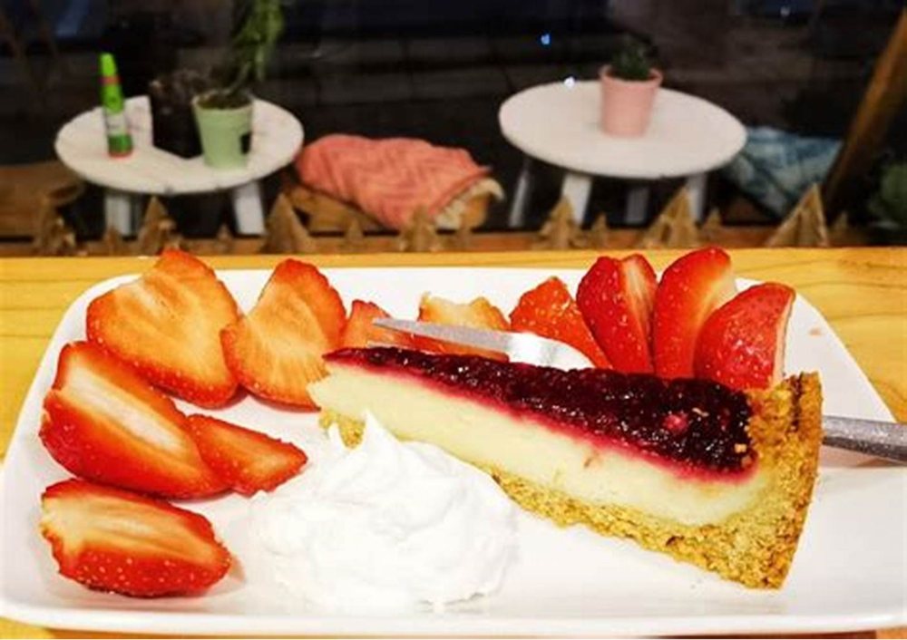 Una porción de cheesecake con frutillas y crema.