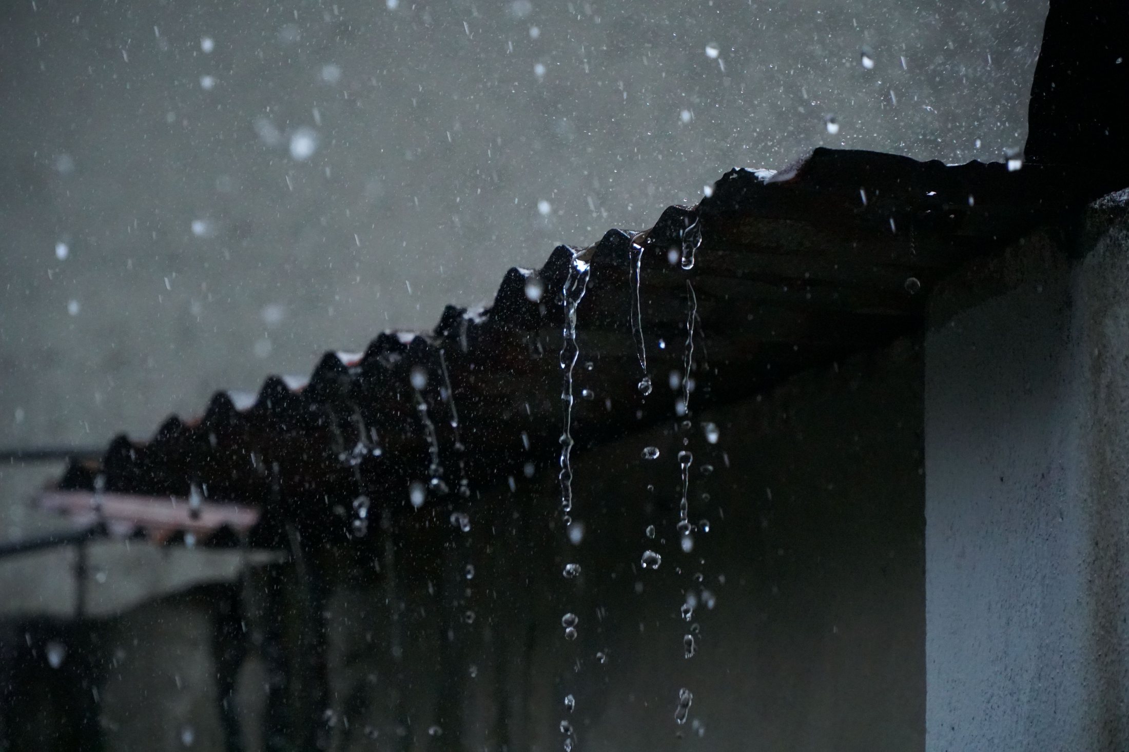 Agua de lluvia cayendo desde el borde de un techo sin canaleta