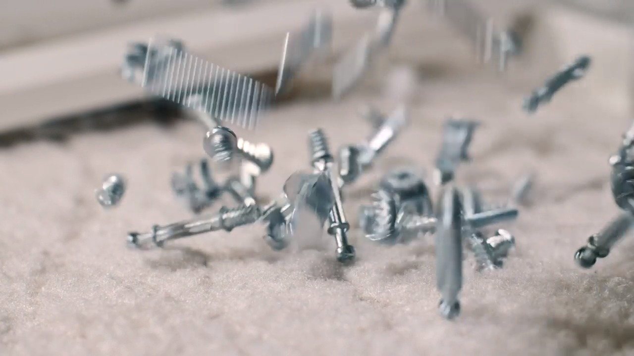 Tornillos cayendo sobre una superficie clara.