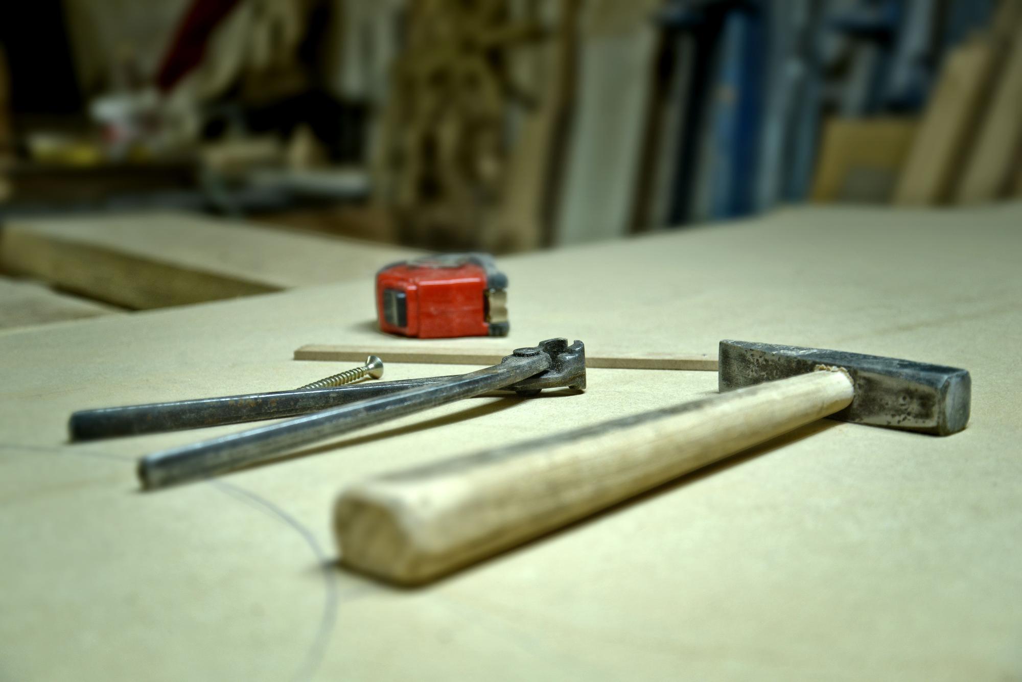 Un martillo y una huincha sobre un mesón de trabajo.