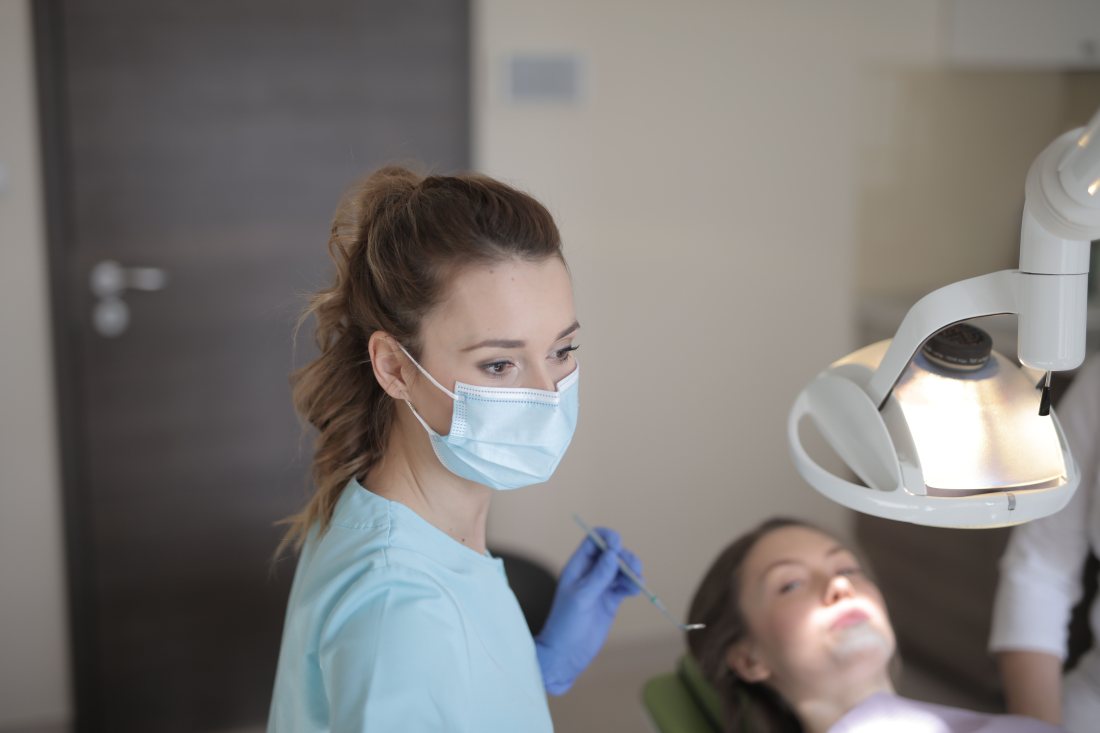 Odontóloga ajustando la lámpara sobre el sillón dental.