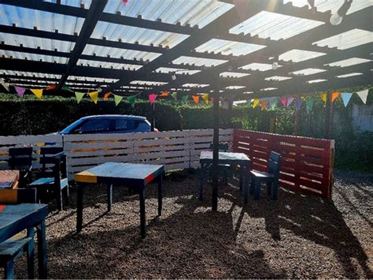 La terraza con la pérgola de policarbonato, las bancas de colores y los banderines colgados.