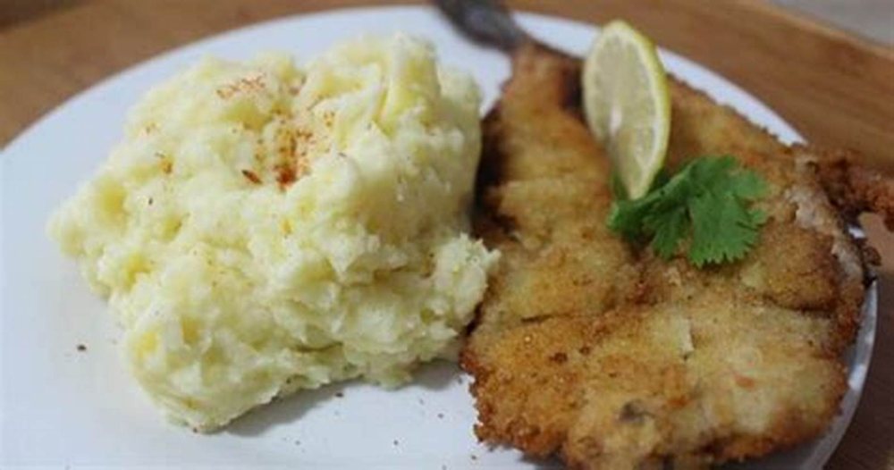 Escalopa apanada con puré, en el plato.