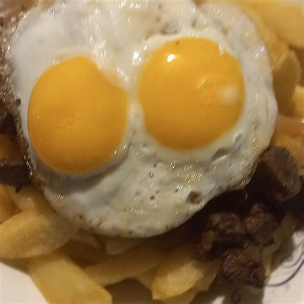 Papas fritas con dos huevos fritos encima.