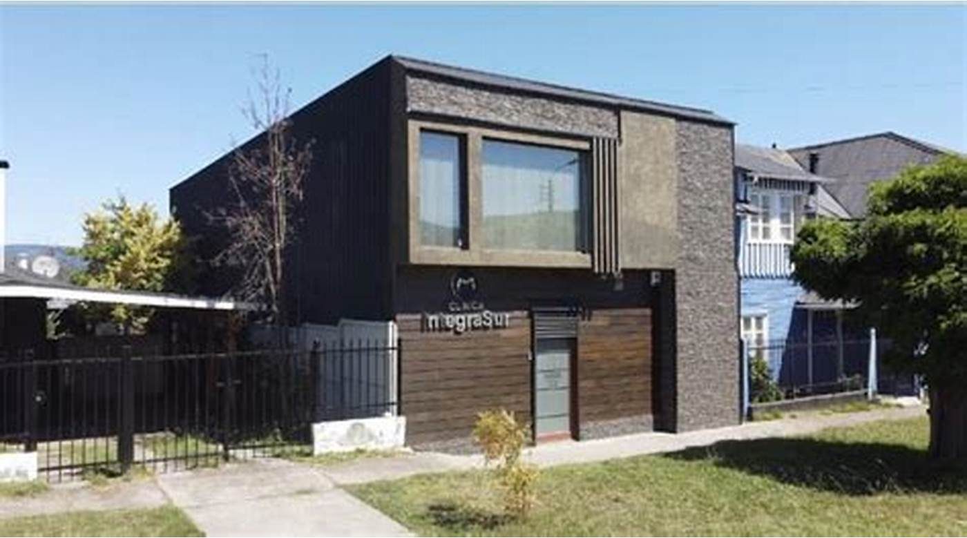 El edificio de la clínica visto desde la calle, revestido en madera y piedra.