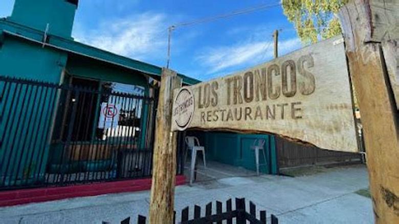 El letrero tallado de Los Troncos sobre los postes de madera de la entrada.