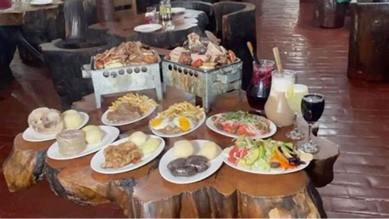 Mesa de troncos con varios platos servidos y las copas puestas.