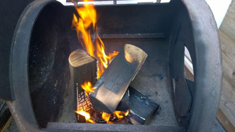 Leña partida ardiendo dentro de un horno de fierro.