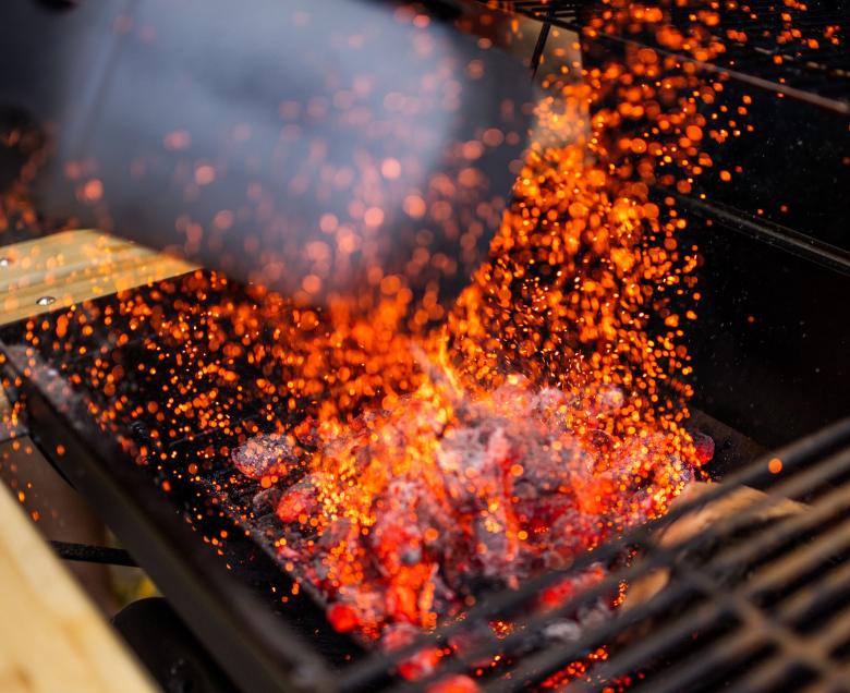 Brasas al rojo bajo la parrilla, con las chispas saltando.