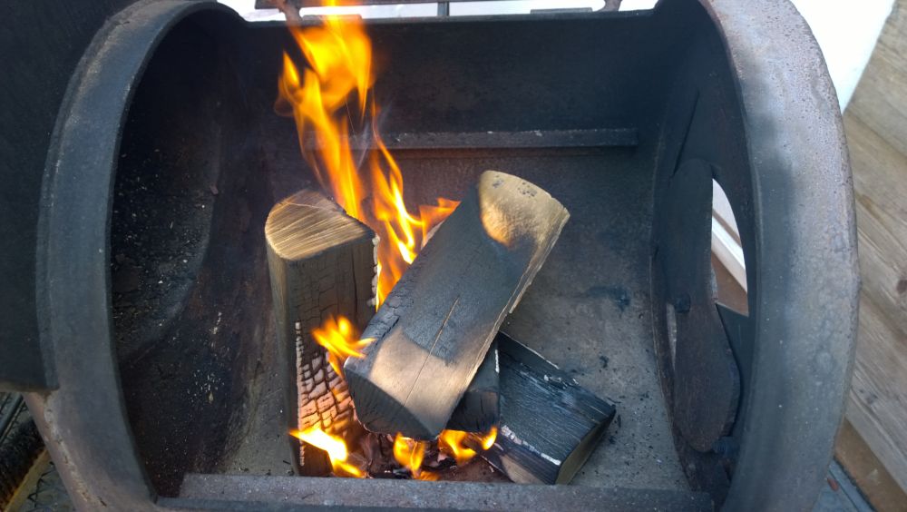 Leña ardiendo dentro de un horno de fierro.