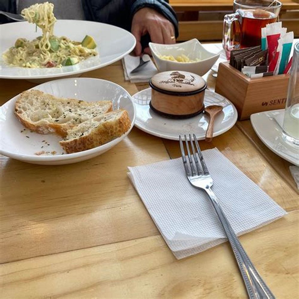 Pasta, pan tostado y un café servidos en la mesa de madera.