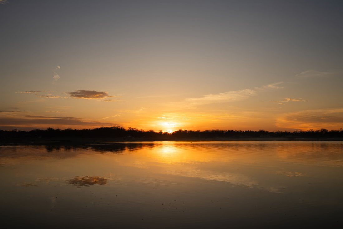 Puesta de sol reflejada en el agua quieta.